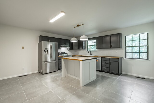 kitchen with wooden counters, pendant lighting, a center island, stainless steel appliances, and light tile patterned floors