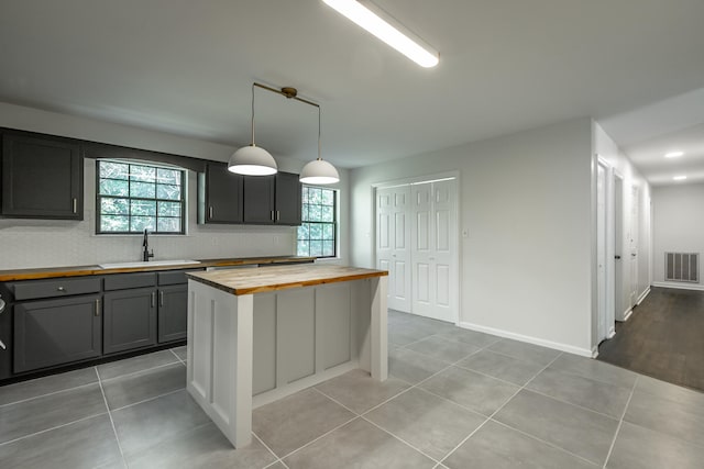 kitchen featuring decorative light fixtures, a center island, a healthy amount of sunlight, and butcher block counters