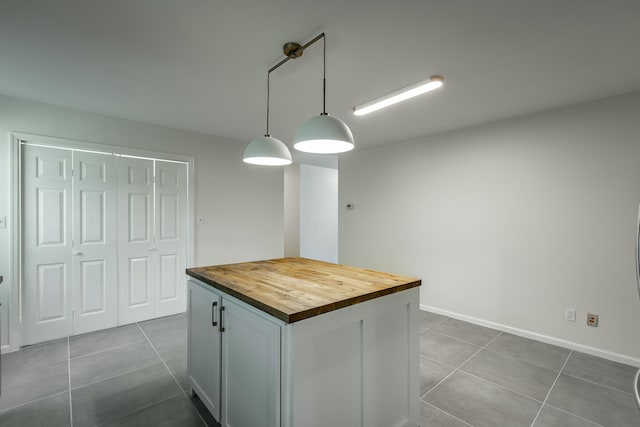 kitchen featuring dark tile patterned flooring, hanging light fixtures, wooden counters, and a kitchen island