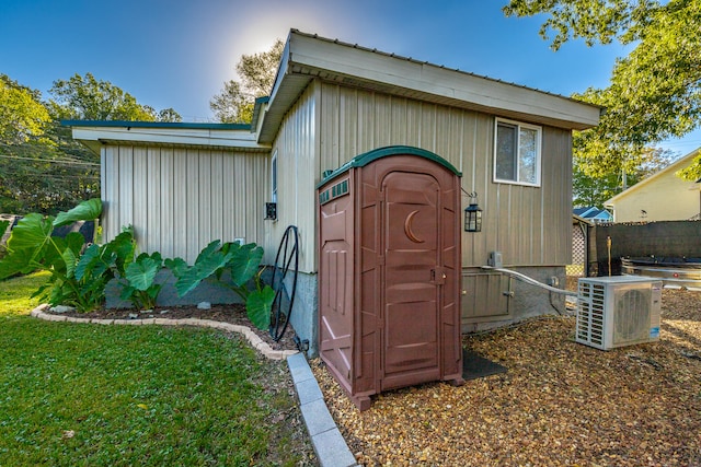 view of outbuilding featuring ac unit and a lawn