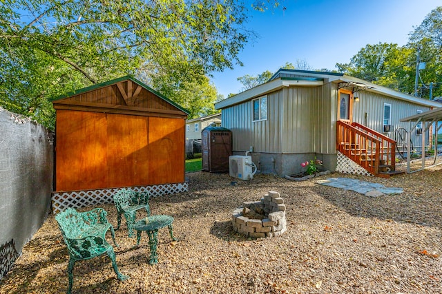 exterior space with ac unit, a storage unit, and a fire pit