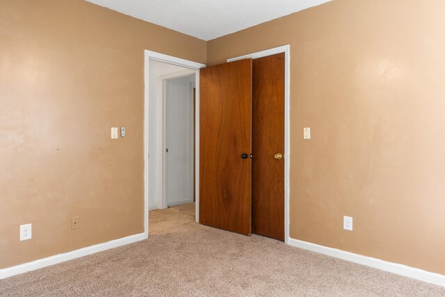 unfurnished bedroom with a closet and light carpet