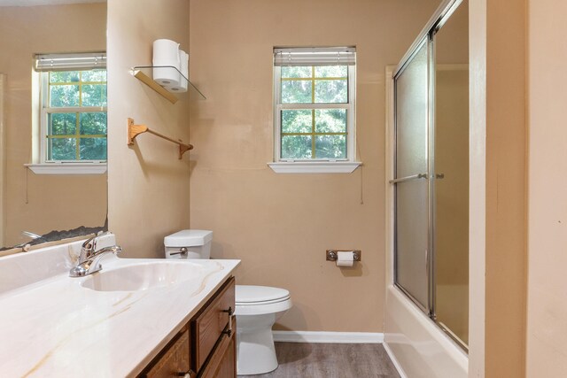 full bathroom featuring plenty of natural light, enclosed tub / shower combo, vanity, and toilet