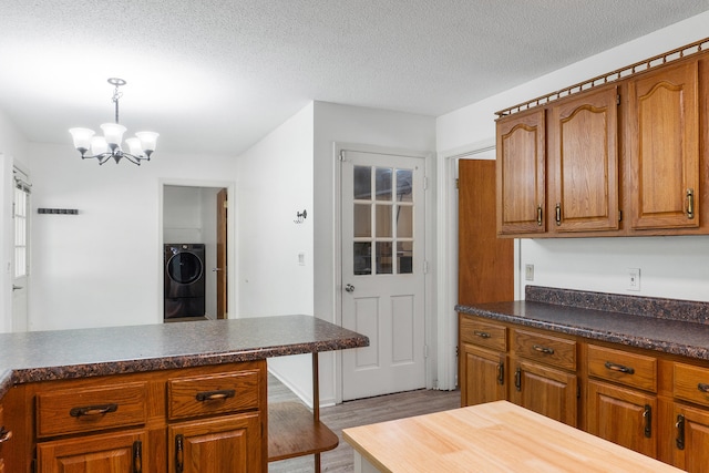 kitchen with hanging light fixtures, a textured ceiling, a chandelier, washer / clothes dryer, and light wood-type flooring