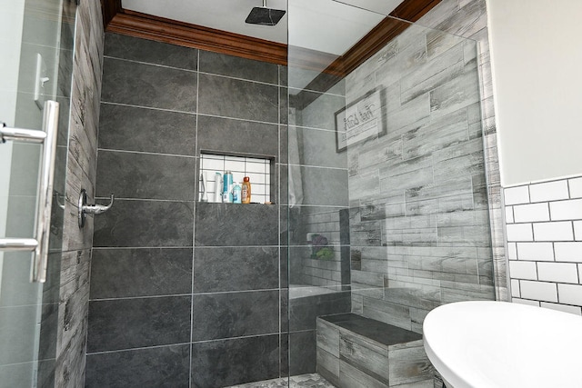 bathroom with ornamental molding, tile walls, and a tile shower