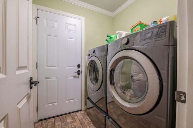 laundry area featuring brick patterned floor, washing machine and clothes dryer, crown molding, and laundry area
