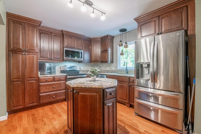 kitchen featuring appliances with stainless steel finishes, light wood-type flooring, sink, and a kitchen island