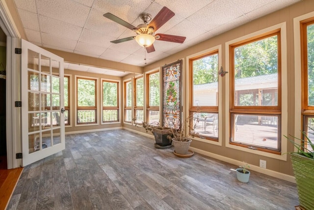 unfurnished sunroom featuring a drop ceiling and ceiling fan