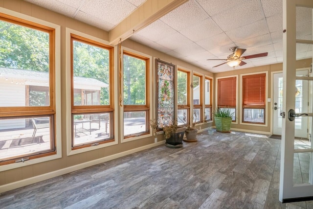 unfurnished sunroom featuring baseboards, wood finished floors, and a paneled ceiling