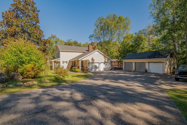 view of front of property with driveway, a garage, a chimney, and an outbuilding