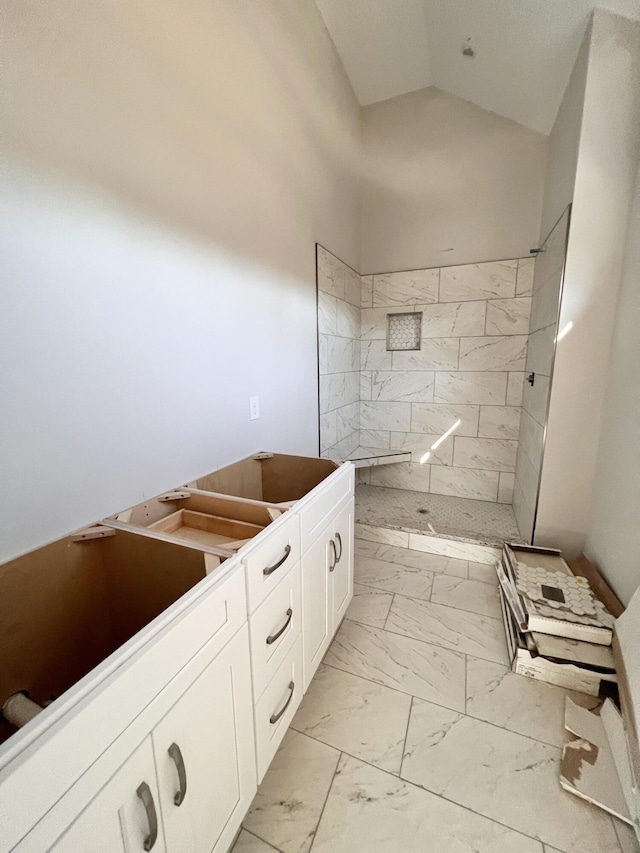 bathroom featuring a tile shower and lofted ceiling