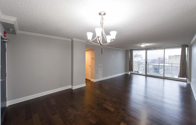 empty room featuring dark hardwood / wood-style flooring, ornamental molding, a textured ceiling, an inviting chandelier, and a wall of windows