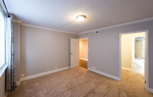 unfurnished bedroom featuring light carpet, ensuite bathroom, a textured ceiling, and ornamental molding