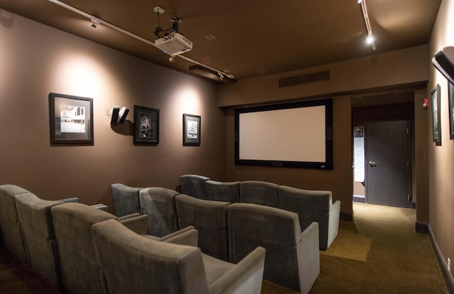 carpeted home theater room featuring rail lighting