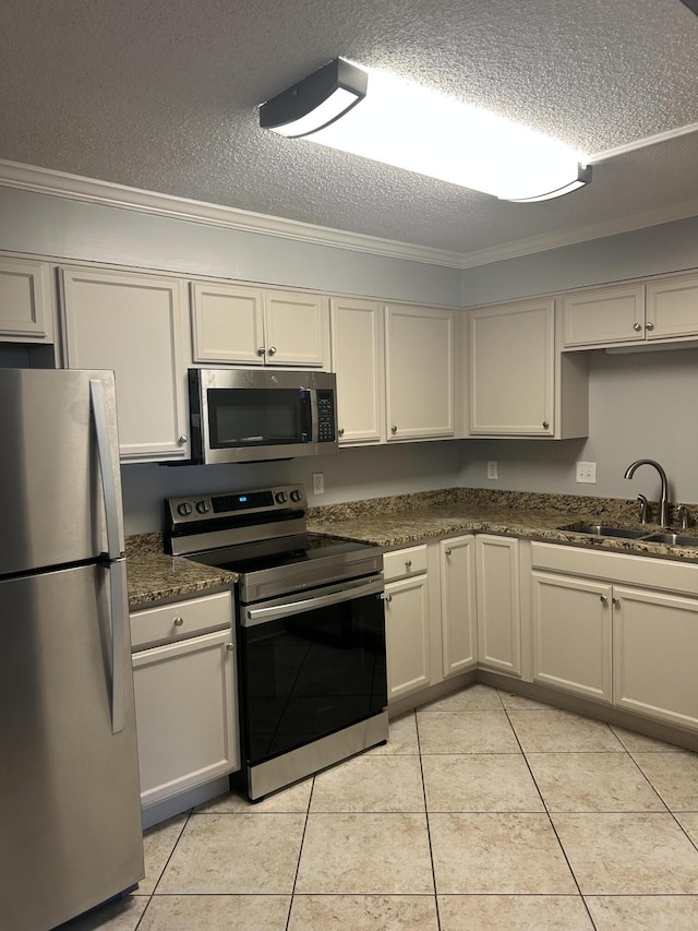 kitchen featuring appliances with stainless steel finishes, a textured ceiling, crown molding, sink, and light tile patterned floors