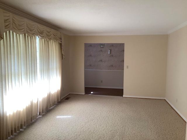 carpeted spare room featuring a healthy amount of sunlight and crown molding