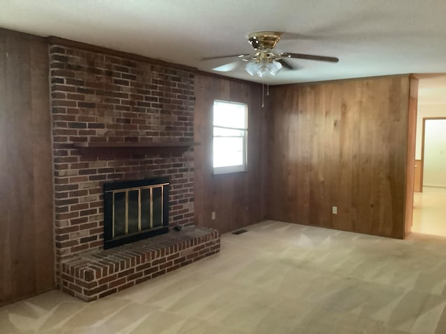 unfurnished living room with a brick fireplace, wooden walls, and light carpet