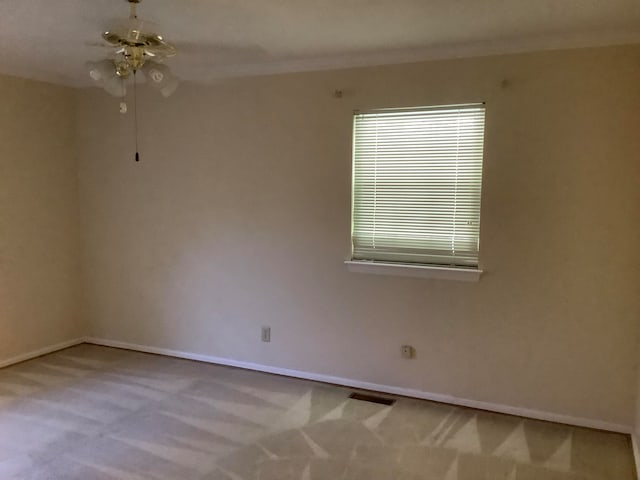 carpeted spare room featuring ornamental molding and ceiling fan