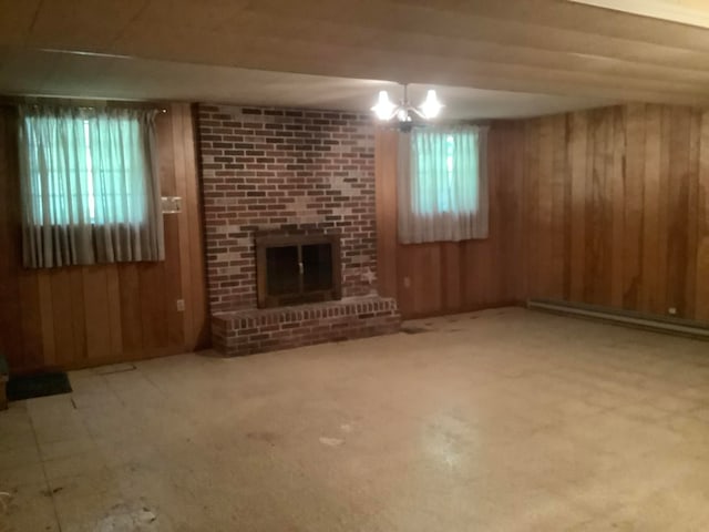 unfurnished living room with a brick fireplace, baseboard heating, and wood walls