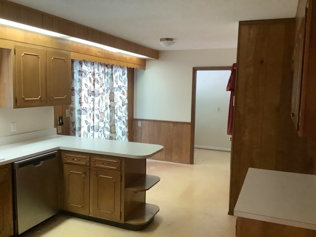 kitchen with kitchen peninsula, wood walls, and stainless steel dishwasher