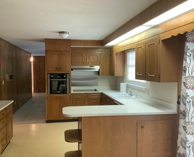 kitchen featuring black electric cooktop, kitchen peninsula, sink, and oven