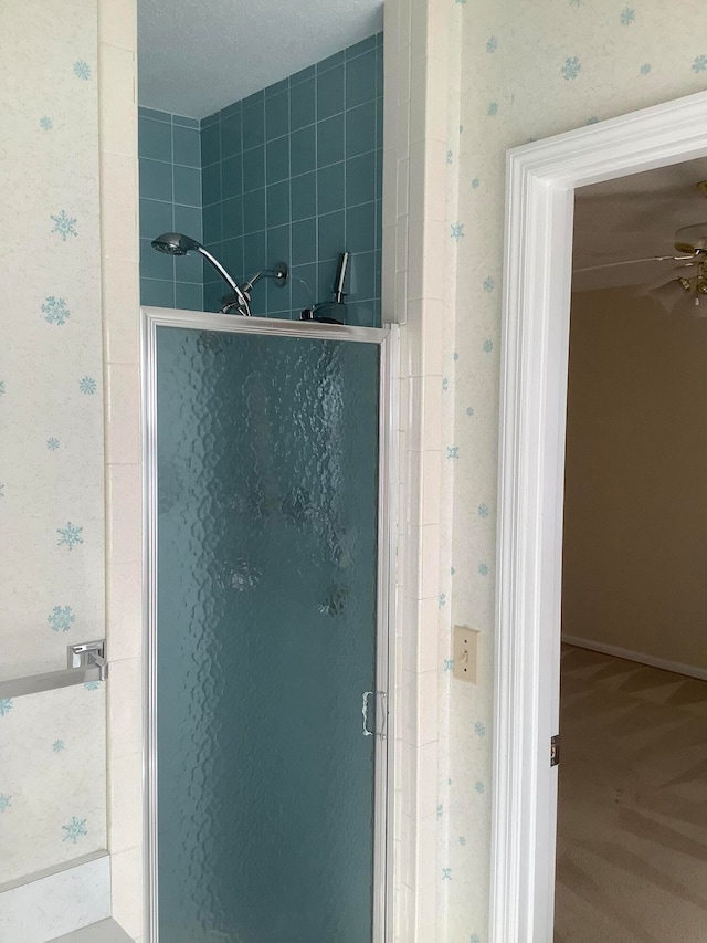 bathroom with a shower with shower door and a textured ceiling