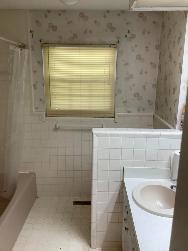 bathroom with shower / bath combo with shower curtain, vanity, and tile walls