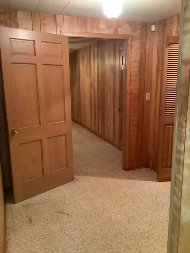 hall featuring wood walls and light colored carpet