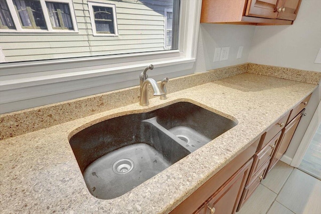 room details featuring light stone counters, light tile patterned floors, and sink