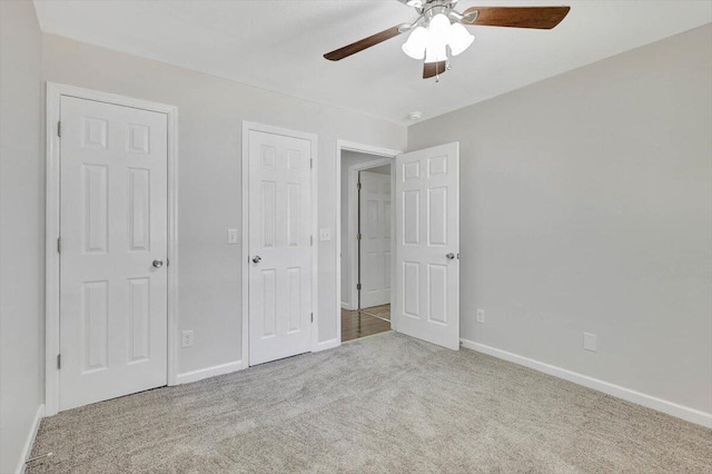 unfurnished bedroom featuring ceiling fan, two closets, and light colored carpet