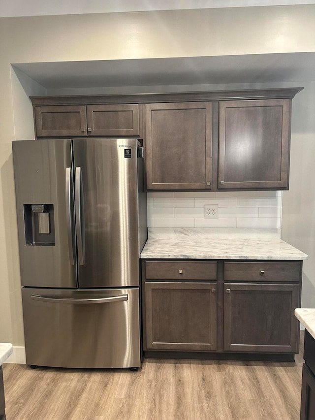 kitchen with dark brown cabinetry, stainless steel fridge, and light hardwood / wood-style floors