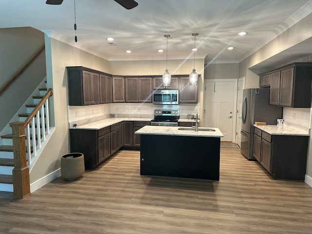 kitchen featuring a kitchen island with sink, pendant lighting, stainless steel appliances, backsplash, and hardwood / wood-style flooring