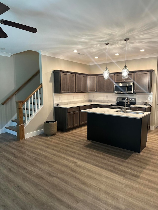 kitchen with a kitchen island with sink, dark brown cabinets, sink, dark hardwood / wood-style floors, and appliances with stainless steel finishes