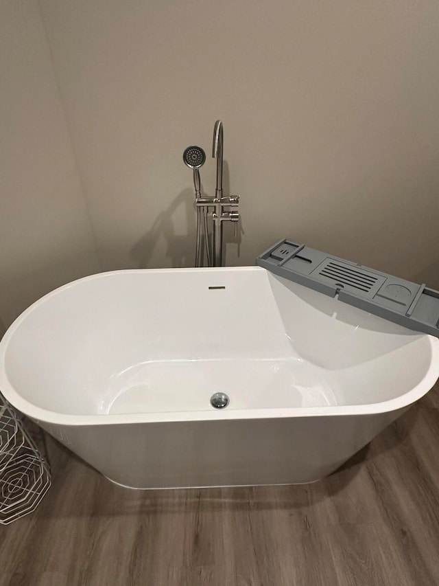 details featuring a tub to relax in and hardwood / wood-style floors