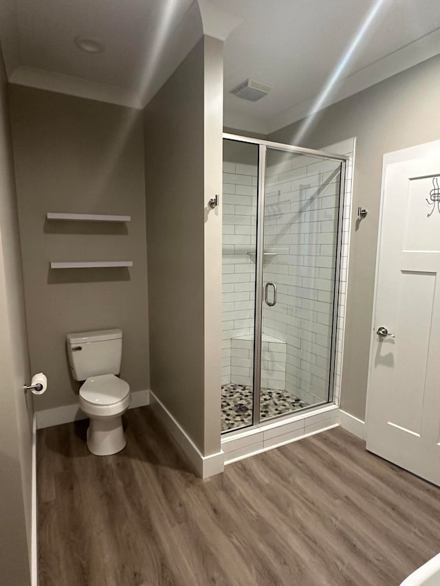 bathroom with crown molding, hardwood / wood-style floors, toilet, and a shower with door