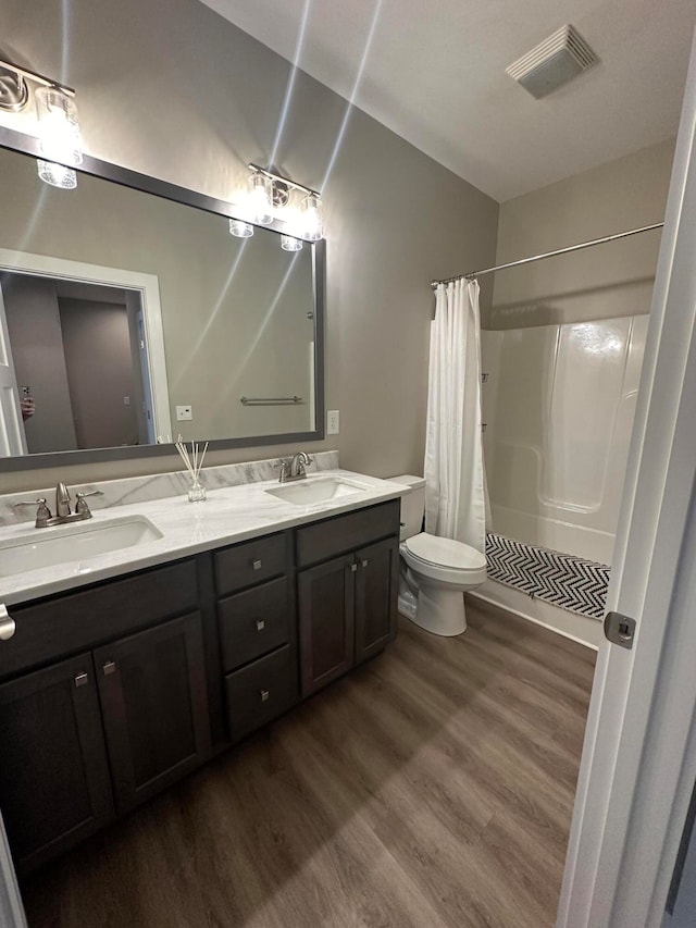 bathroom featuring hardwood / wood-style flooring, vanity, toilet, and curtained shower