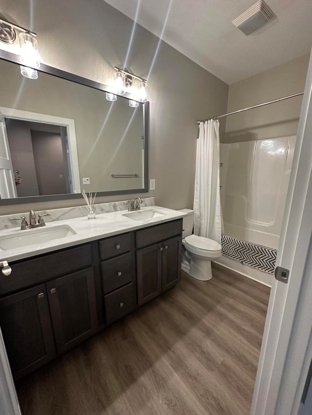 bathroom with walk in shower, hardwood / wood-style flooring, vanity, and toilet