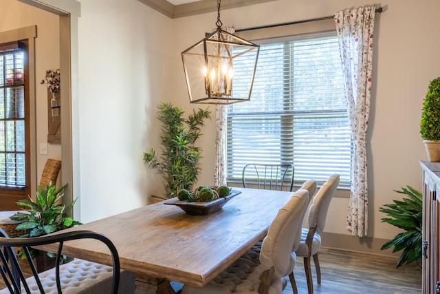 dining area with crown molding, wood-type flooring, a chandelier, and plenty of natural light