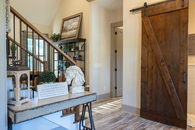 office space featuring hardwood / wood-style flooring, lofted ceiling, and a barn door