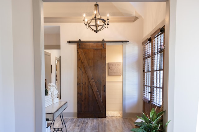 foyer with crown molding, a barn door, a notable chandelier, and wood-type flooring