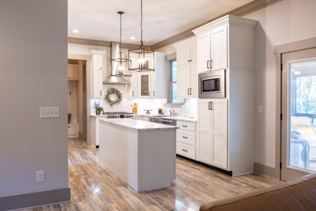 kitchen with a center island, stainless steel appliances, pendant lighting, white cabinets, and light hardwood / wood-style flooring