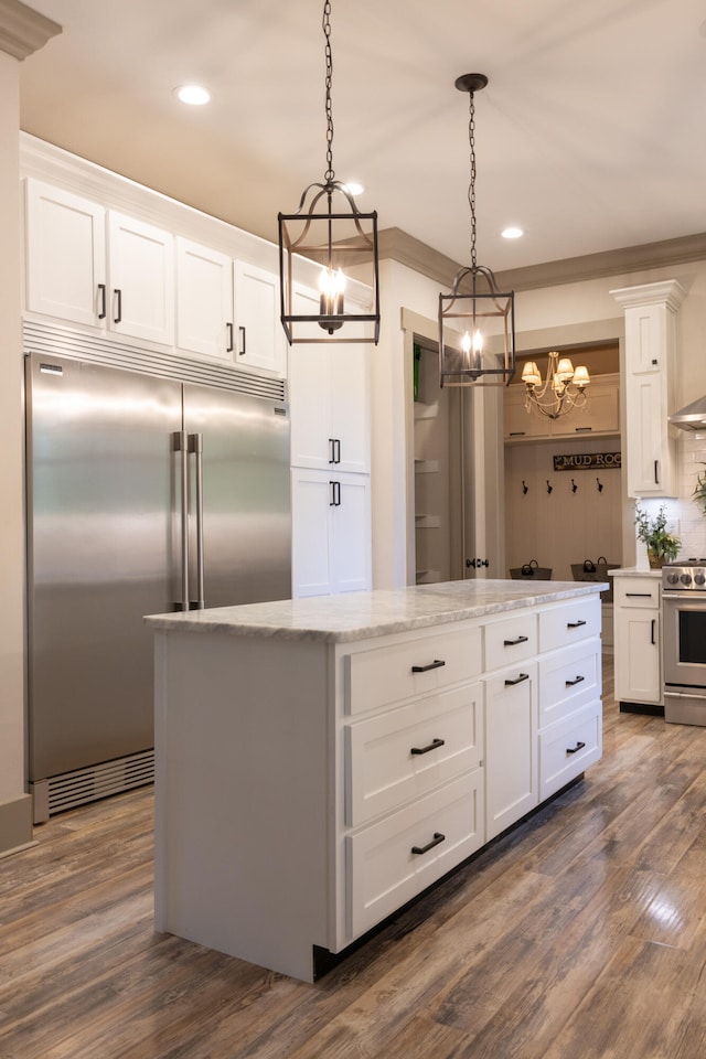 kitchen featuring a center island, pendant lighting, white cabinetry, appliances with stainless steel finishes, and dark hardwood / wood-style flooring