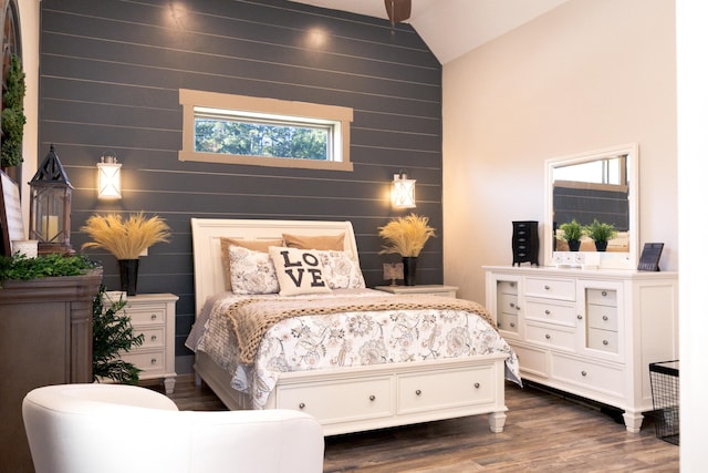 bedroom with multiple windows, dark hardwood / wood-style floors, wood walls, and vaulted ceiling