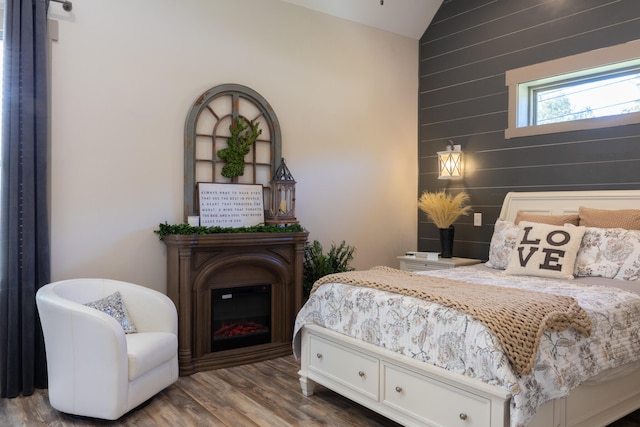 bedroom featuring lofted ceiling, wood walls, and wood-type flooring