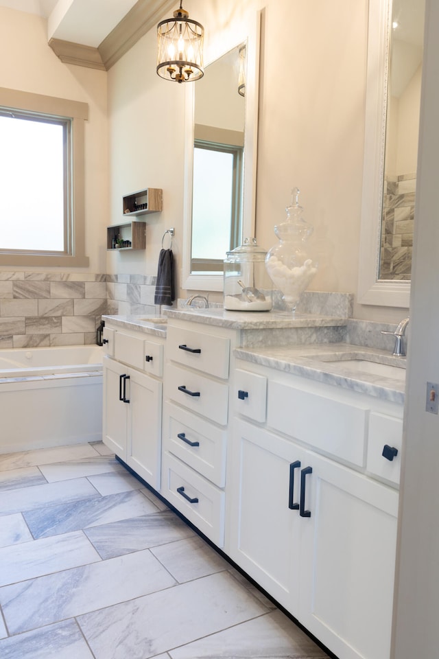 bathroom with an inviting chandelier, vanity, crown molding, and a bath