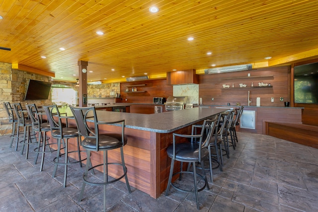 kitchen featuring backsplash, wooden ceiling, and a kitchen breakfast bar