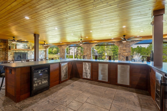 view of patio with wine cooler, an outdoor kitchen, an outdoor bar, and ceiling fan