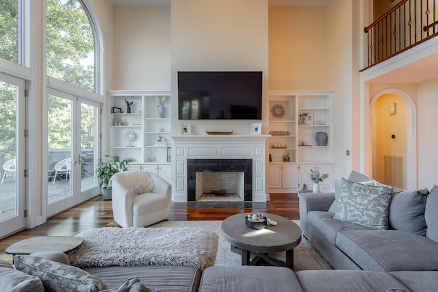 living room with a tiled fireplace, wood-type flooring, and a high ceiling