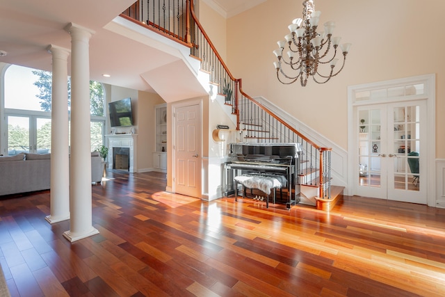 entryway with wood-type flooring, french doors, ornate columns, a high ceiling, and ornamental molding