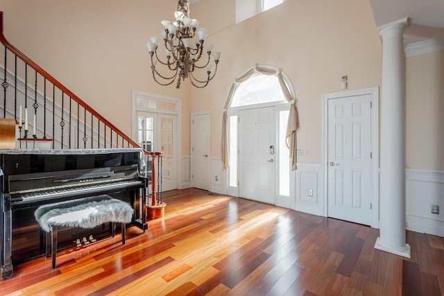 entryway featuring ornate columns, wood-type flooring, and a towering ceiling